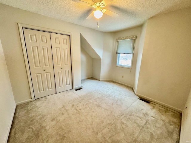 bonus room with ceiling fan, light colored carpet, and a textured ceiling