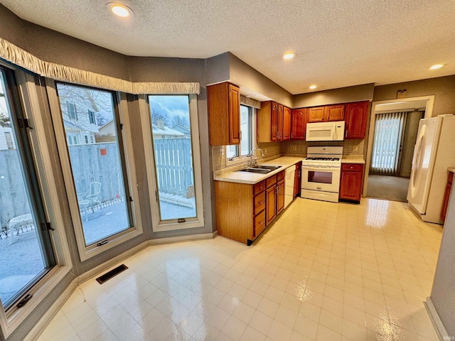 kitchen with sink, white appliances, tasteful backsplash, and a textured ceiling