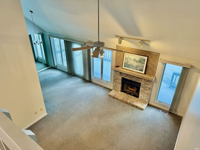 unfurnished living room featuring ceiling fan, plenty of natural light, carpet flooring, and a fireplace