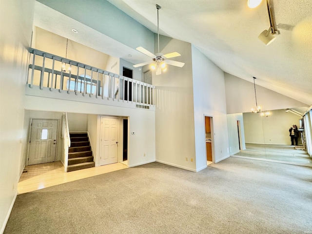 unfurnished living room with carpet floors, ceiling fan with notable chandelier, a towering ceiling, and a textured ceiling