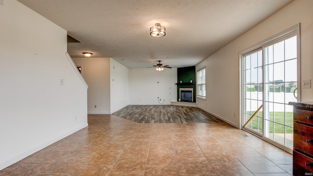 unfurnished living room featuring a large fireplace, ceiling fan, and a wealth of natural light