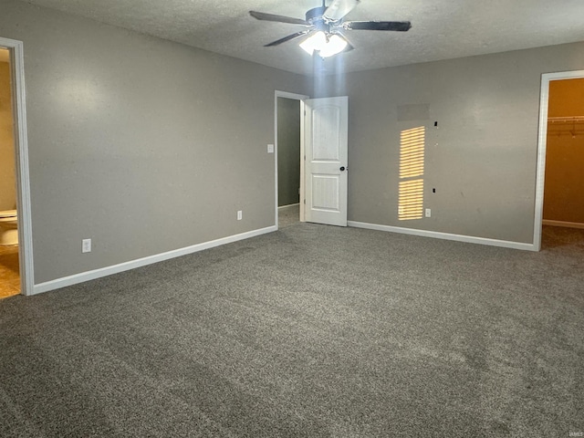 unfurnished bedroom featuring a closet, ceiling fan, carpet, and a spacious closet