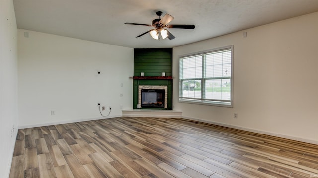 unfurnished living room featuring a fireplace, ceiling fan, and light wood-type flooring