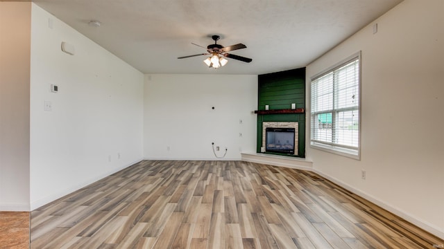 unfurnished living room featuring a fireplace, light hardwood / wood-style floors, and ceiling fan