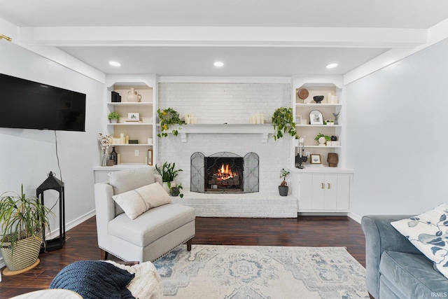 living room with built in features, beamed ceiling, a brick fireplace, and dark hardwood / wood-style floors