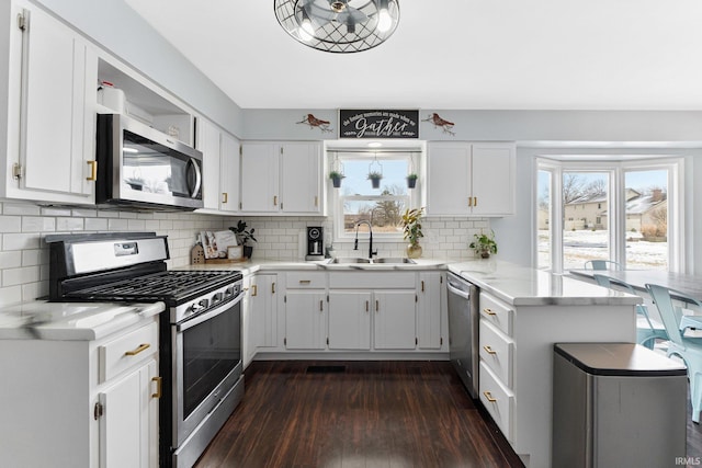 kitchen featuring white cabinets, kitchen peninsula, appliances with stainless steel finishes, and tasteful backsplash