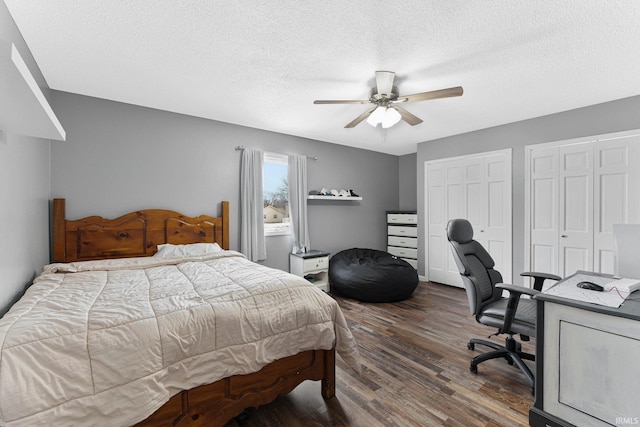 bedroom featuring ceiling fan, dark hardwood / wood-style floors, a textured ceiling, and two closets