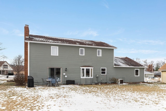 snow covered back of property featuring central AC