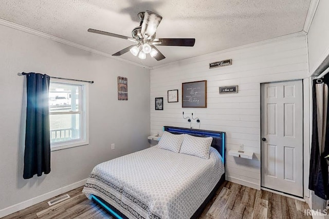 bedroom with hardwood / wood-style flooring, a textured ceiling, ceiling fan, and ornamental molding