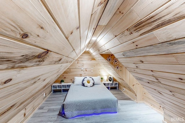 bedroom with vaulted ceiling, wood walls, wood ceiling, and light wood-type flooring