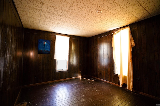 empty room with dark hardwood / wood-style floors and wood walls