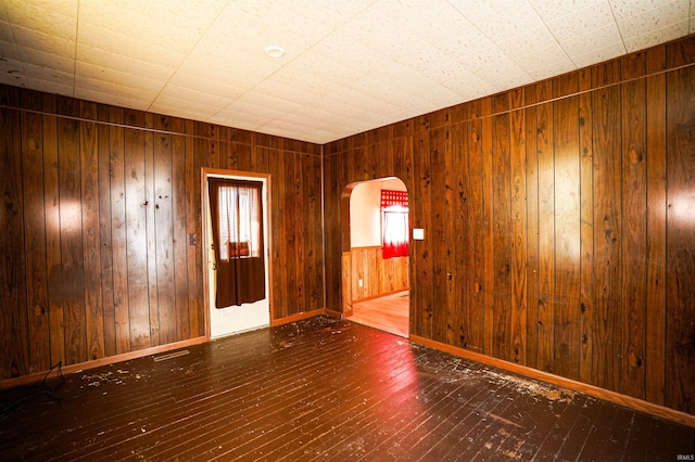 empty room with hardwood / wood-style floors and wood walls