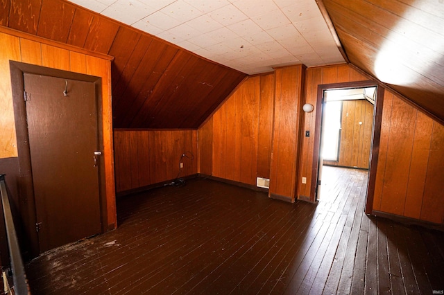 additional living space featuring vaulted ceiling, wood walls, and dark hardwood / wood-style floors