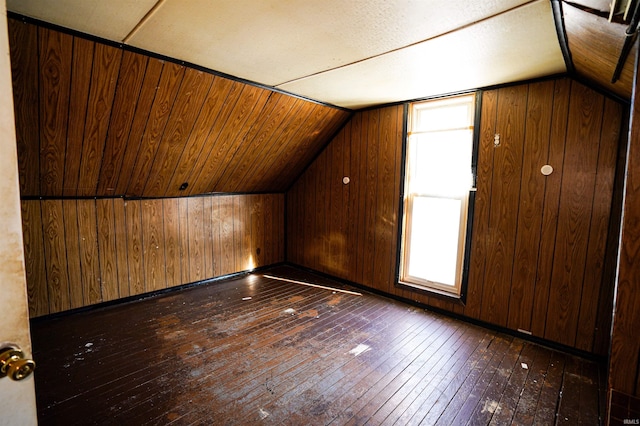 additional living space featuring vaulted ceiling, wood walls, and dark hardwood / wood-style floors