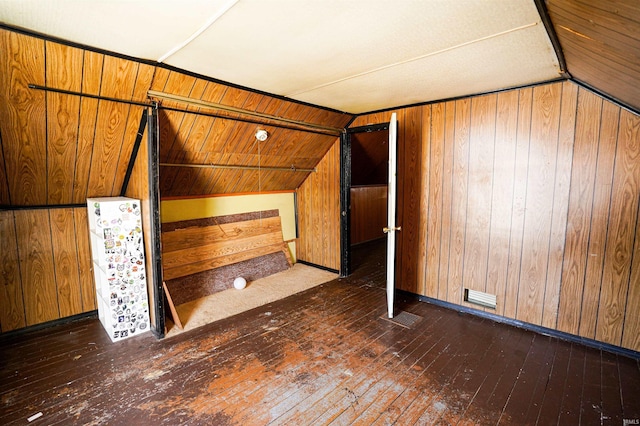 bonus room featuring wooden walls, dark hardwood / wood-style floors, and lofted ceiling