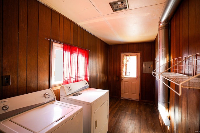 washroom with dark hardwood / wood-style floors, wood walls, and washing machine and dryer