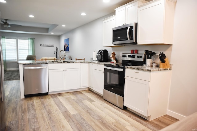 kitchen featuring light hardwood / wood-style floors, kitchen peninsula, white cabinetry, and stainless steel appliances