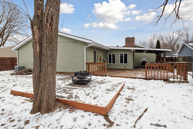 snow covered property featuring a wooden deck, a fire pit, and central air condition unit