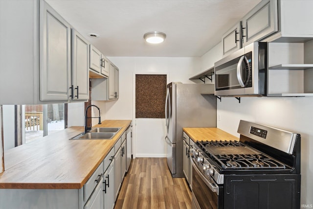 kitchen featuring sink, gray cabinets, dark wood-type flooring, and stainless steel appliances