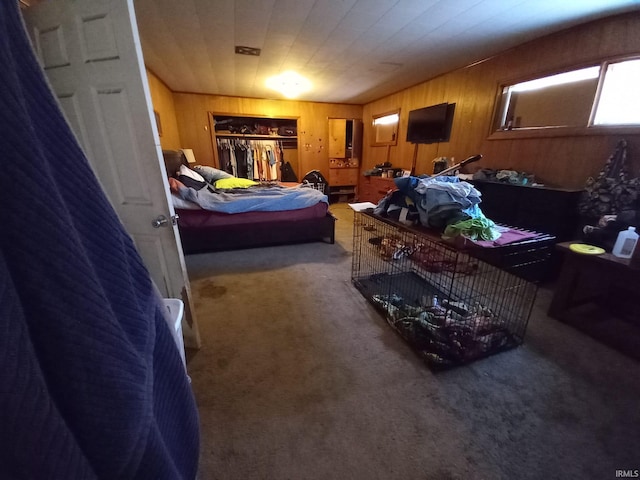 carpeted bedroom with a closet and wood walls