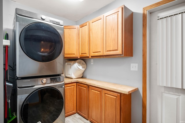 laundry room featuring cabinets and stacked washer / drying machine