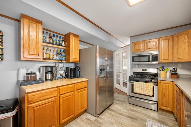 kitchen featuring butcher block counters, light hardwood / wood-style floors, stainless steel appliances, crown molding, and french doors