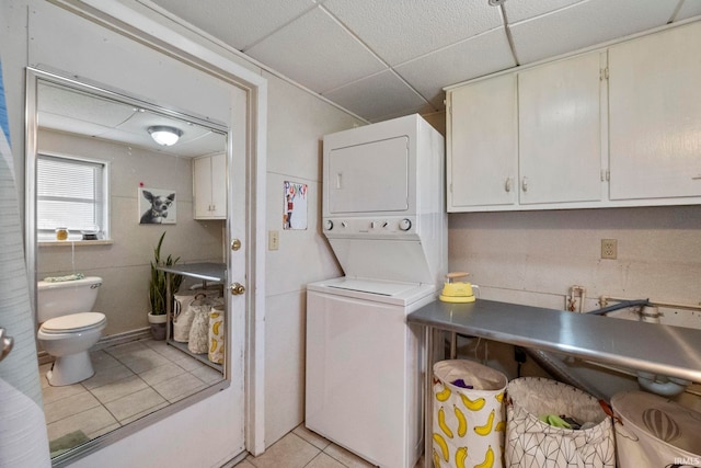 laundry room with stacked washer / dryer and light tile patterned floors