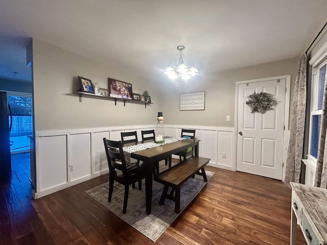 dining space with dark hardwood / wood-style floors and an inviting chandelier