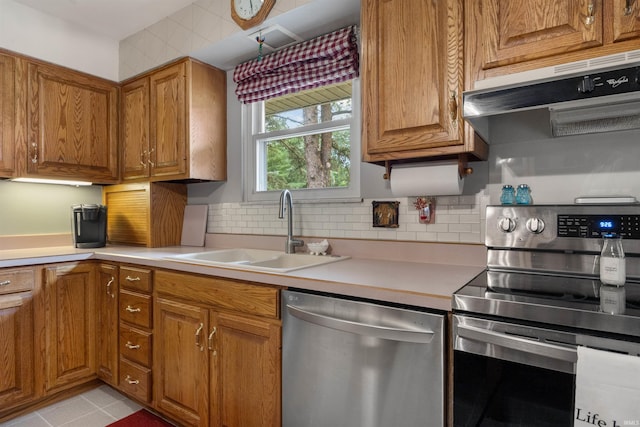 kitchen with sink, backsplash, light tile patterned flooring, and appliances with stainless steel finishes