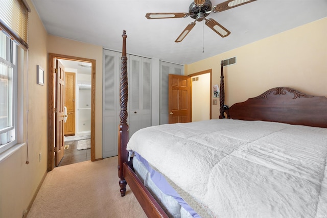 carpeted bedroom featuring ceiling fan and two closets