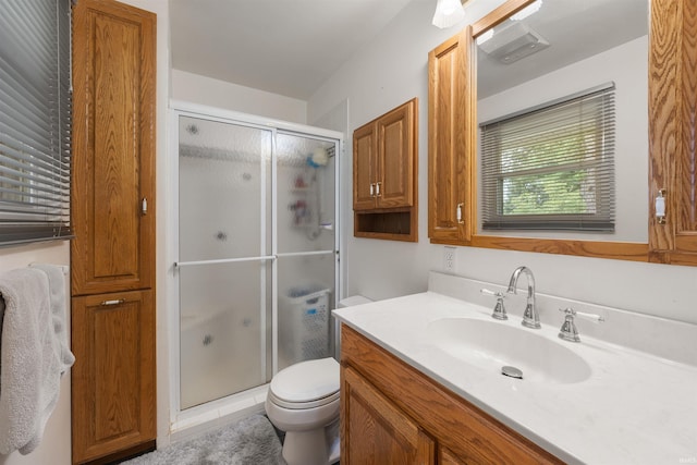 bathroom featuring vanity, toilet, and a shower with shower door