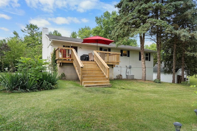 rear view of house with a wooden deck and a lawn