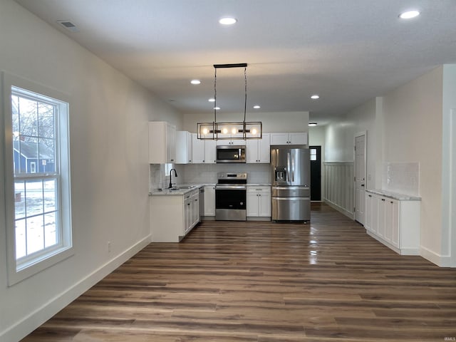 kitchen featuring decorative light fixtures, sink, white cabinets, stainless steel appliances, and dark wood-type flooring