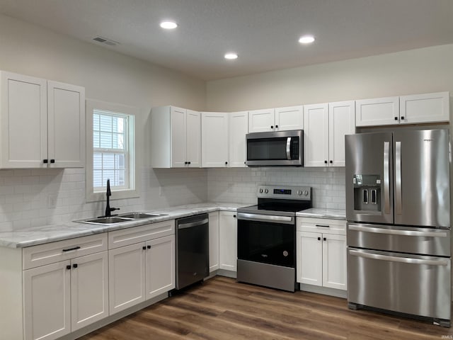 kitchen with sink, stainless steel appliances, white cabinets, and light stone countertops