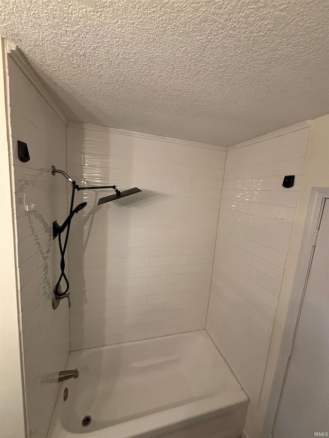 bathroom with tiled shower / bath and a textured ceiling