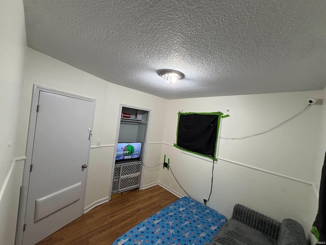 bedroom with dark hardwood / wood-style floors and a textured ceiling