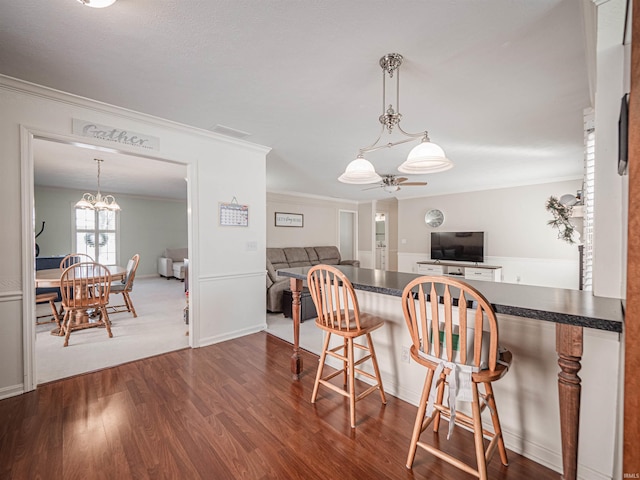 kitchen featuring ornamental molding, dark hardwood / wood-style flooring, a breakfast bar, and decorative light fixtures