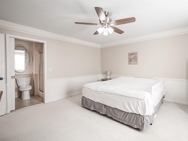 carpeted bedroom with crown molding, ceiling fan, and ensuite bath