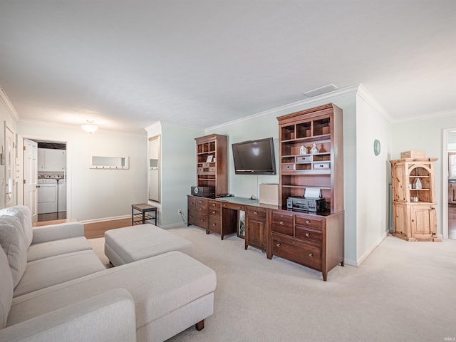 living room with washer and dryer, ornamental molding, built in desk, and light carpet