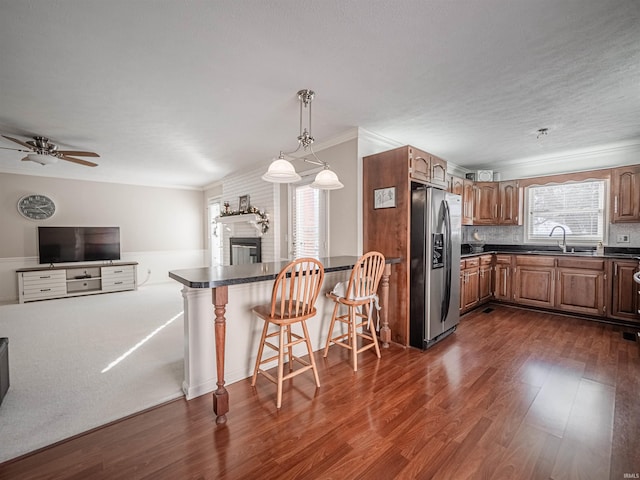 kitchen featuring a breakfast bar, decorative light fixtures, sink, stainless steel fridge, and kitchen peninsula