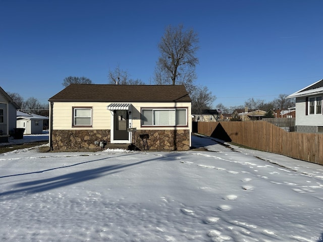 view of front of home with stone siding and fence