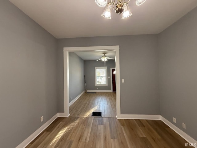 spare room with an inviting chandelier and wood-type flooring