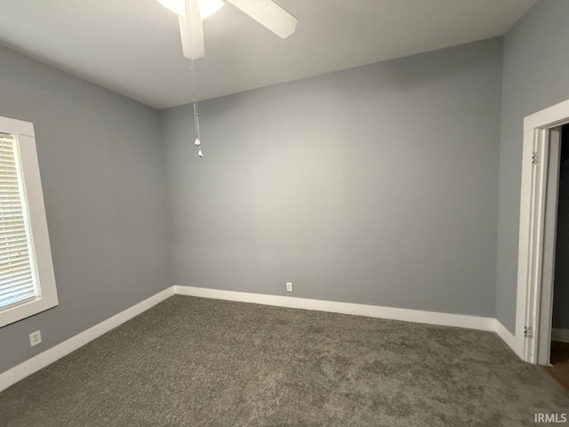 empty room featuring ceiling fan and dark colored carpet