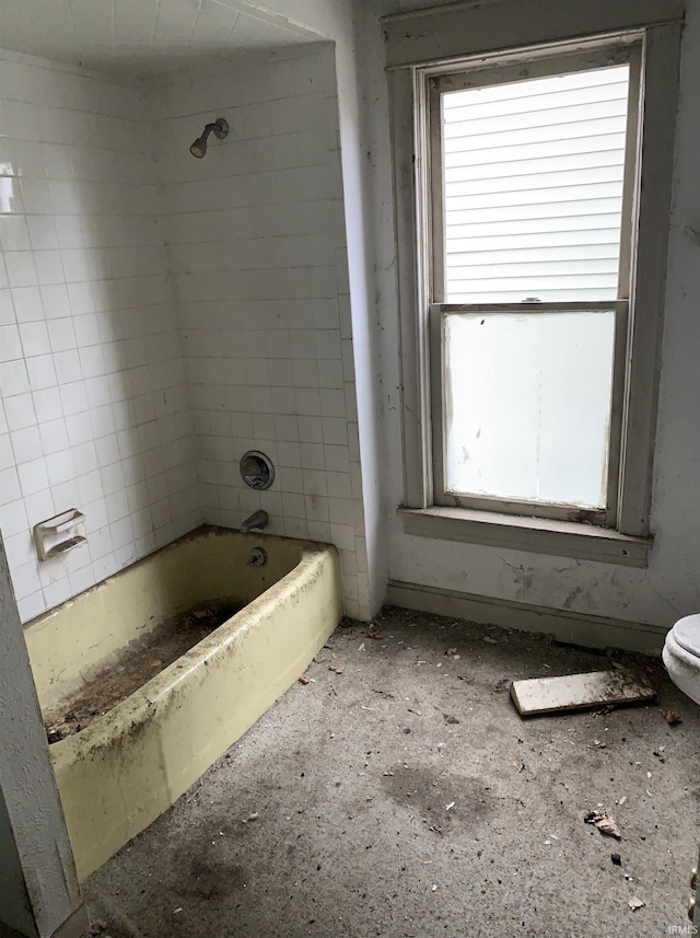 bathroom featuring tiled shower / bath combo, plenty of natural light, and toilet