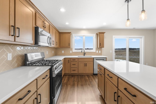 kitchen with dark wood-type flooring, sink, tasteful backsplash, hanging light fixtures, and appliances with stainless steel finishes