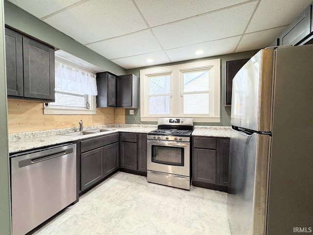 kitchen with stainless steel appliances, dark brown cabinets, sink, and a drop ceiling