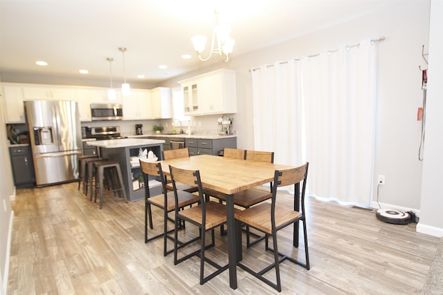 dining space with a notable chandelier, sink, and light wood-type flooring