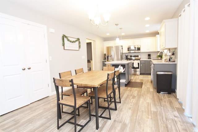 dining area with a chandelier, sink, and light wood-type flooring