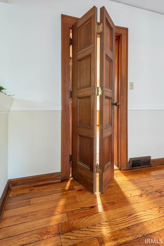 hall featuring ornamental molding and light hardwood / wood-style flooring