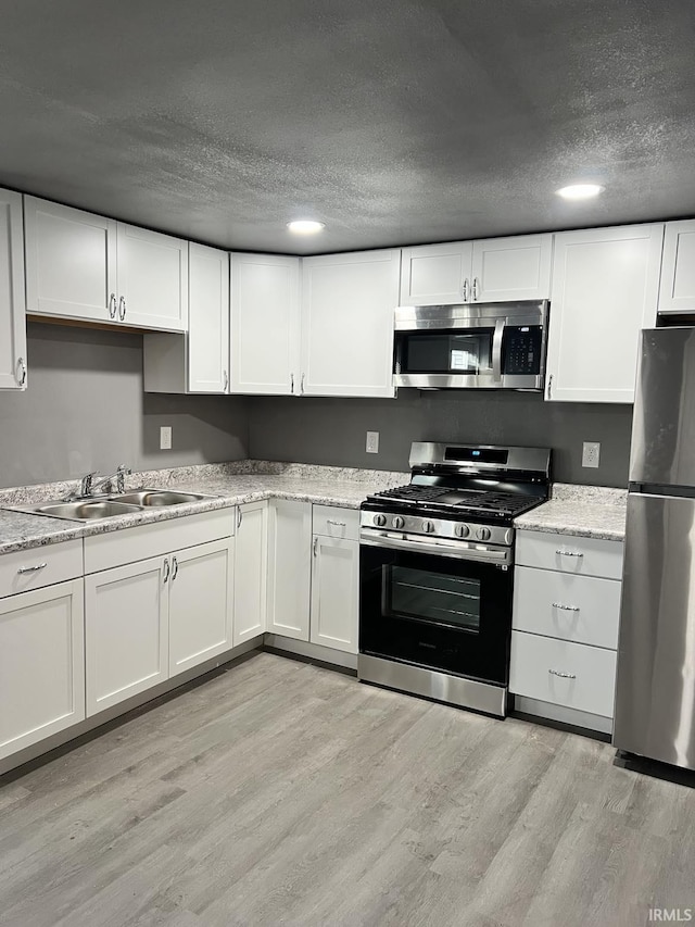 kitchen with sink, white cabinets, and appliances with stainless steel finishes